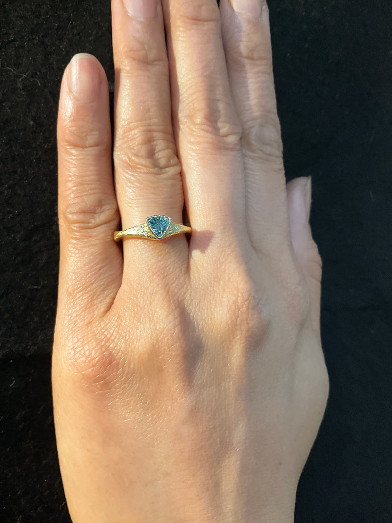 Forged Trillion Cut Blue Zircon Ring in 18k gold on hand