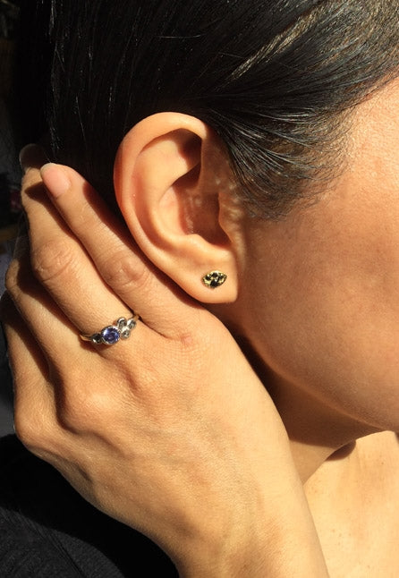 Black diamond stud earrings worn with purple sapphire ring 