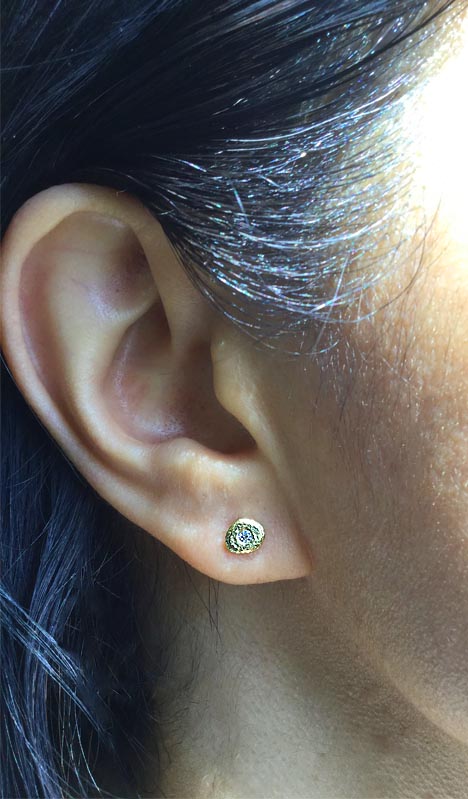 Single Pebble stud earrings in 18k gold with diamond on ear